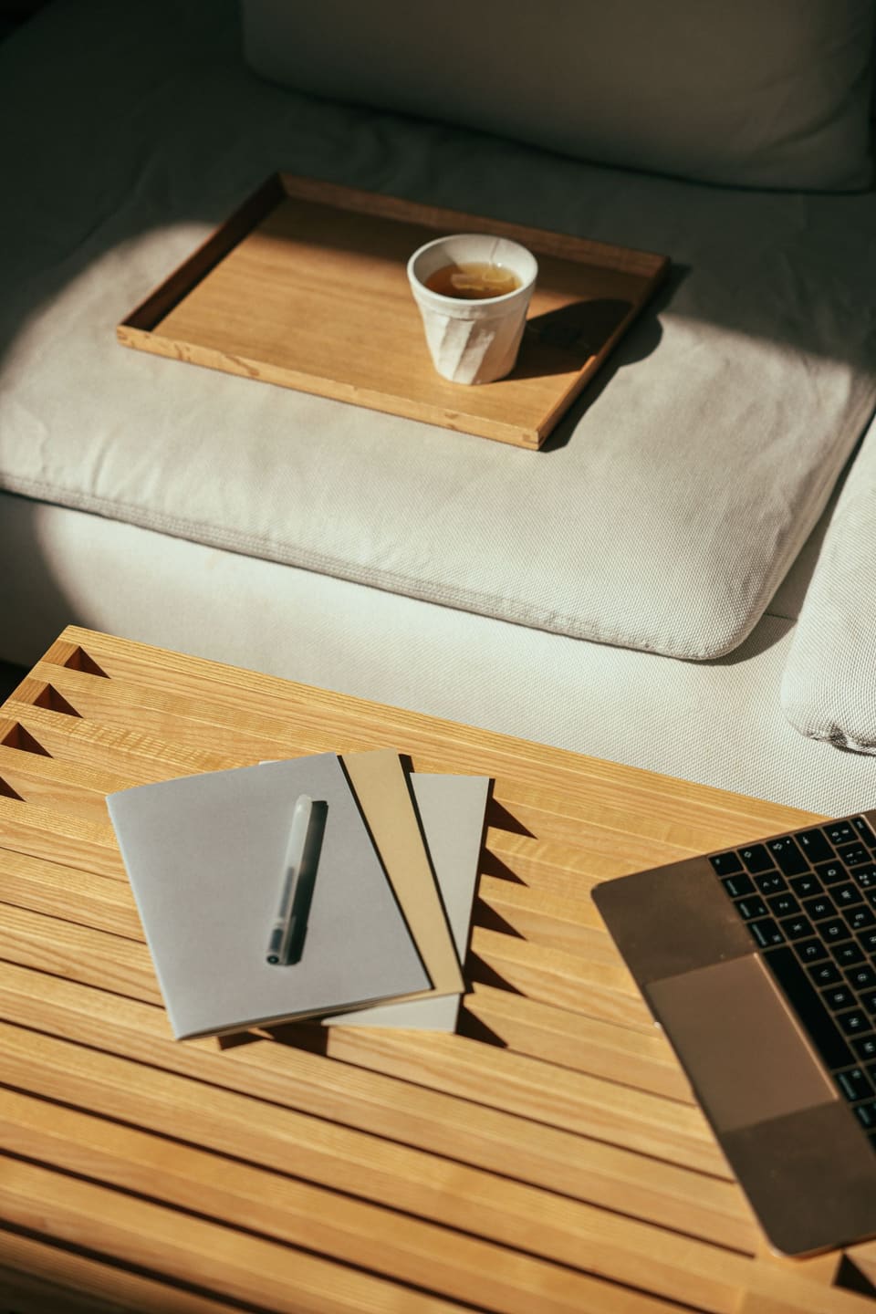 Natural light on wooden work desk with laptop and notebook representing intentional engineering.